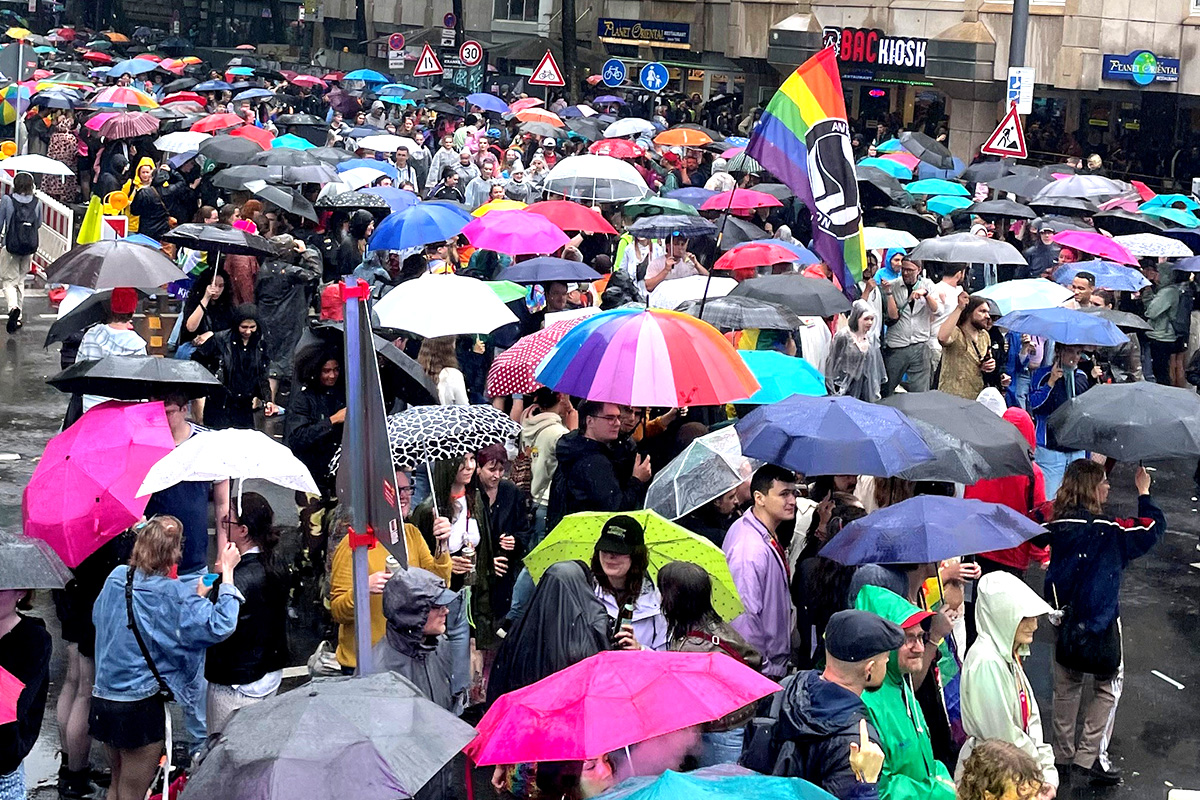 Viele Menschen mit Regenschirmen feiern den CSD auf den Straßen. 