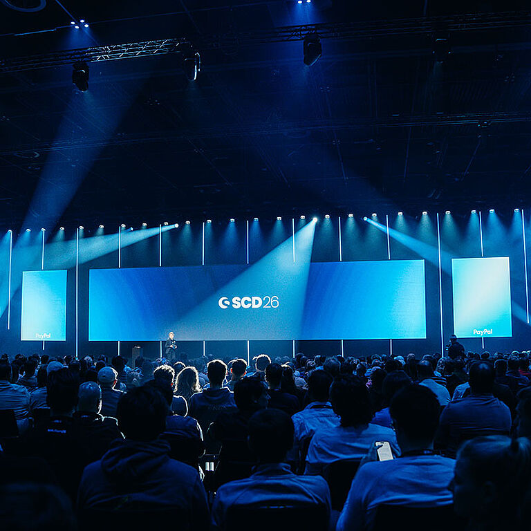 Große LED-Bühne mit Lichtinszenierung und Publikum beim Shopware Community Day im Confex Köln, technisch umgesetzt von müllermusic Veranstaltungstechnik.
