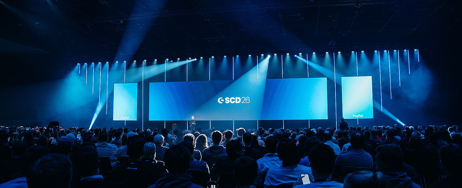 Große LED-Bühne mit Lichtinszenierung und Publikum beim Shopware Community Day im Confex Köln, technisch umgesetzt von müllermusic Veranstaltungstechnik.
